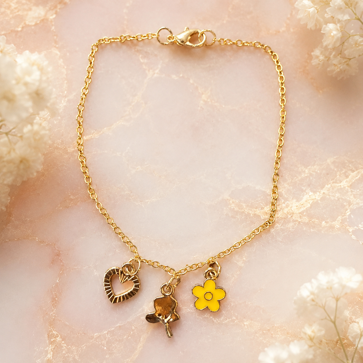 Pulsera de oro con dije de corazón, rosa y flor amarilla